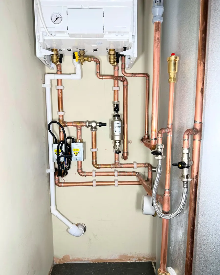 Neat parallel copper pipework under a boiler, with filter, valves and expansion vessel