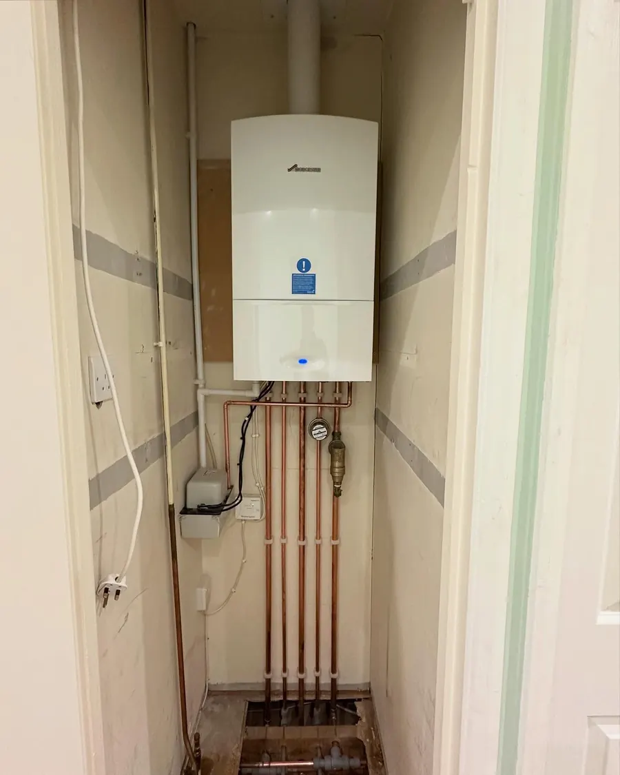 A Worcester Bosch combi boiler in a cupboard with straight vertical copper pipework