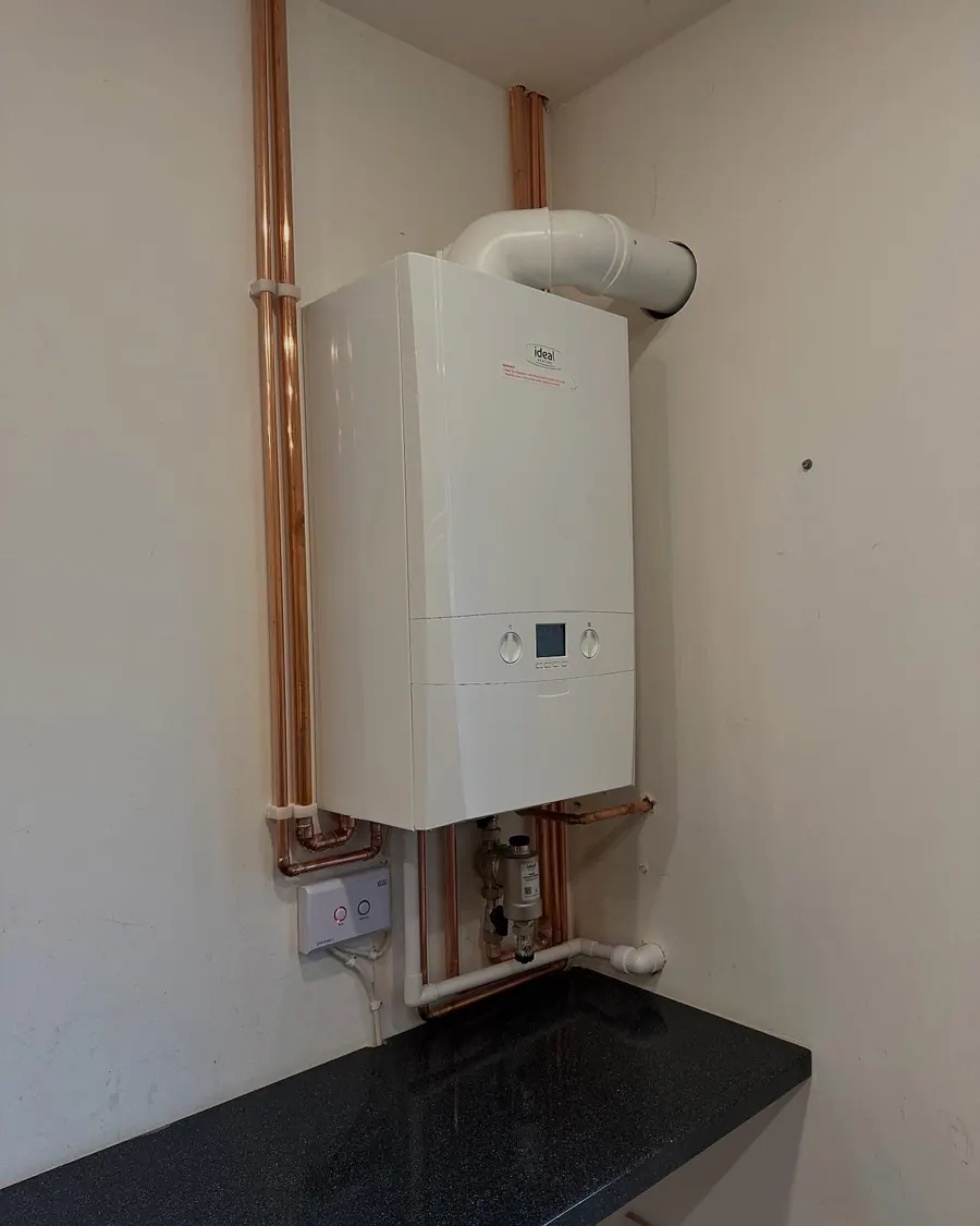 A new white combi boiler on the wall with copper pipework, replacing an old Powermax