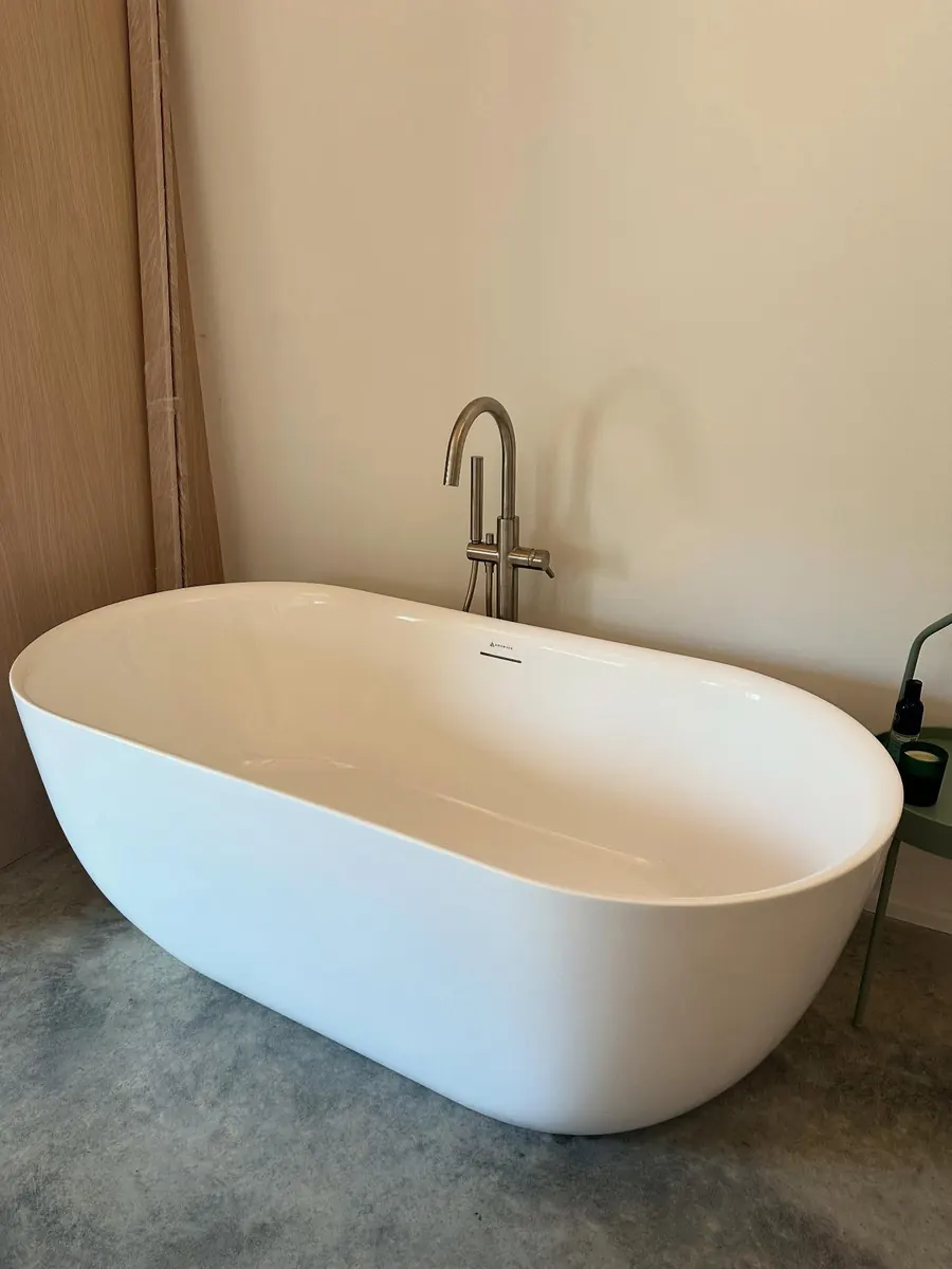A freestanding bath with a floor-standing tap on a polished concrete floor